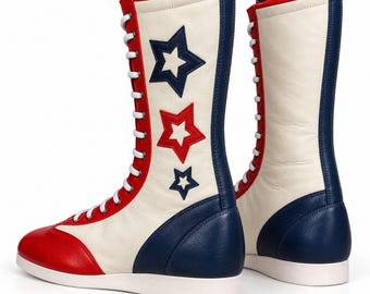 May include: A pair of high-top lace-up boots featuring a cream-colored shaft with red and blue star appliqués. The boots have a red toe cap, a blue heel counter, and white laces. The design includes red and blue trim along the vertical lace panel.