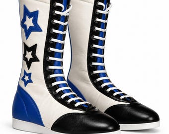 May include: A pair of mid-calf lace-up boots featuring a white base with black and blue accents. The boots have white laces, a black toe cap, and a blue heel panel. The side of each boot is decorated with three star-shaped appliqués in blue and black.