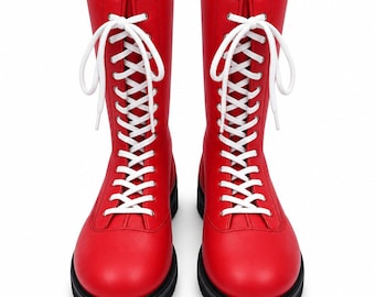 May include: A pair of mid-calf boots in a vibrant red color featuring a smooth finish, rounded toes, and thick black soles. The boots are secured with long white laces threaded through silver-toned eyelets that extend up the front shaft.