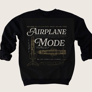 Op de afbeelding: Zwart sweatshirt met een gouden grafisch ontwerp van een vliegtuig met de tekst "AIRPLANE MODE" en de zin "WE GET HIGH LIKE PLANES".
