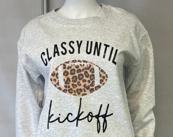 Può includere: Felpa grigia con un grafico di un pallone da calcio con stampa leopardata e il testo "Classy Until Kickoff".