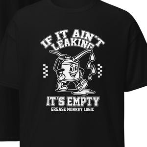 May include: Black t-shirt featuring a cartoon oil can character with the text "IF IT AIN'T LEAKING, IT'S EMPTY" in white. The design includes a checkered pattern and the words "GREASE MONKEY LOGIC". The back of the shirt is plain black.