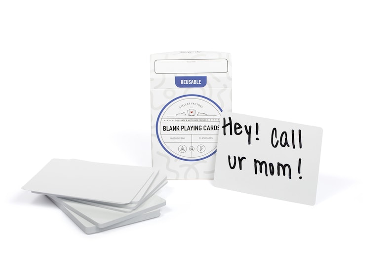 May include: A white box of blank playing cards with the text "BLANK PLAYING CARDS" and "REUSABLE" on the front. The box is sitting on a white surface next to a white card with the text "Hey! Call ur mom!" written in black marker.
