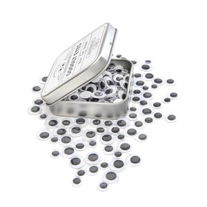 May include: A silver tin with a black and white label that says "Googly Eyes" and contains a variety of googly eyes. The googly eyes are scattered around the tin on a white background.