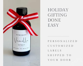 May include: A small glass bottle with a red and white ribbon tied around the neck. The bottle is labeled "Homemade Vanilla Extract with Love, The Smith Family".