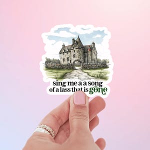 May include: A sticker featuring a watercolor illustration of a stone castle with a green grassy field and the text "sing me a a song of a lass that is gone".