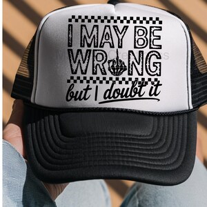 May include: A black and white trucker hat featuring a foam front panel with the black text I MAY BE WRONG but I doubt it, including a skeleton hand middle finger graphic and a checkered border design. The hat has a black brim and mesh back.