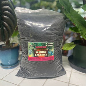 May include: A bag of black worm castings labeled "ENHANCER 100% NATURAL FERTILIZER ORGANIC ODORLESS WORM CASTINGS".