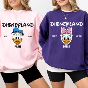 Puede incluir: Una taza de cer&aacute;mica blanca con un asa negra y el texto "But First, Coffee" en negrita negra. La taza se encuentra sobre un fondo borroso, sugiriendo un ambiente acogedor.