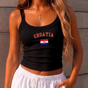May include: A black ribbed tank top featuring the word CROATIA in red block letters arched above a small rectangular Croatian flag with red, white, and blue horizontal stripes and a central red and white checkered crest emblem on the front.
