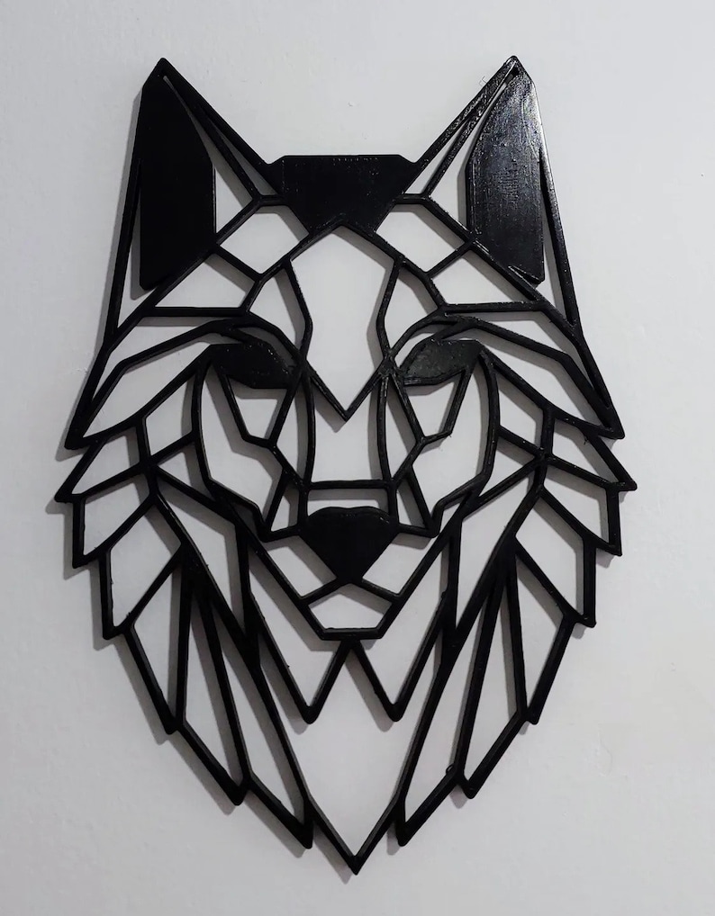 May include: Black geometric wolf head wall decor. The wolf is made of wood and has a black finish. The wolf's head is in a geometric style, with sharp angles and lines.