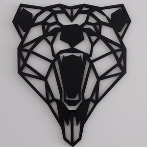 May include: Black geometric bear head wall decor. The bear's mouth is open and its teeth are visible. The bear's eyes are also visible.