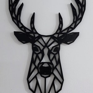 May include: Black geometric deer head wall decor. The deer head is made of wood and has a modern, minimalist design.