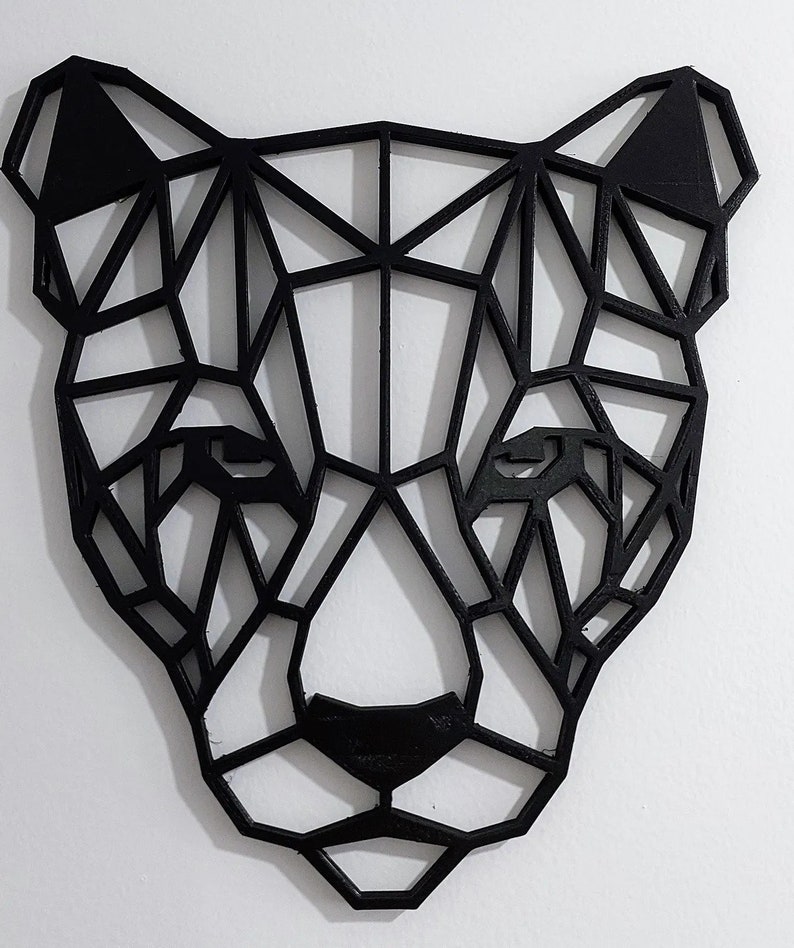May include: Black geometric animal head wall decor. The head is made of wood and is shaped like a panther. The design is modern and minimalist.