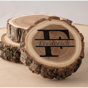 Peut inclure: Ensemble de trois dessous de verre en bois, issus de coupes transversales d'arbres. Le dessus de verre supérieur présente la lettre "F" et le nom "Frederick" gravés en noir. Les dessous de verre ont un grain de bois naturel et des bords en écorce.