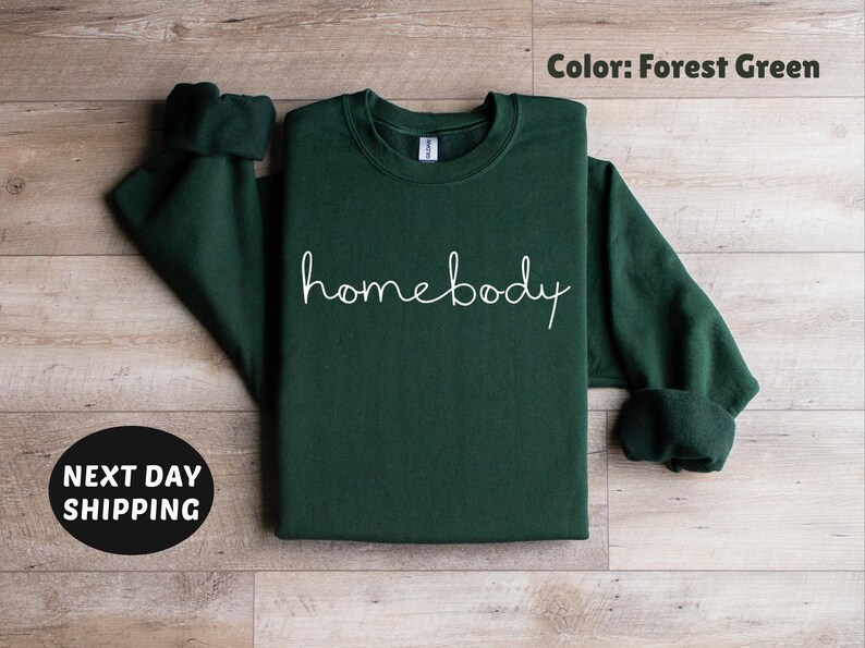 May include: Forest green sweatshirt with the text "homebody" in white lettering.