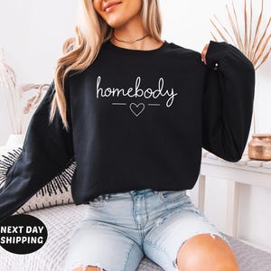 May include: A black sweatshirt with the text "homebody" in white lettering and a small heart graphic.