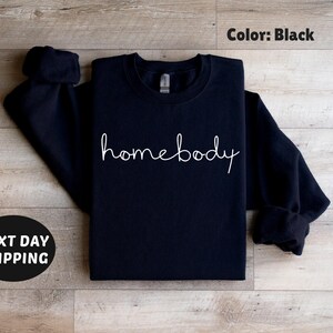 May include: Black sweatshirt with the text "homebody" written in white cursive.