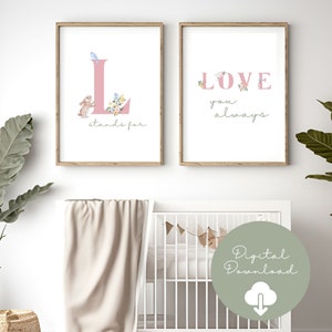 Könnte beinhalten: Zwei gerahmte Kunstdrucke mit einem Kinderzimmer-Thema. Ein Druck zeigt einen rosa Buchstaben "L" mit einem Hasen und floralen Akzenten, dem Text "stands for". Der andere Druck sagt "LOVE you always" in rosa Buchstaben mit floralen Akzenten.