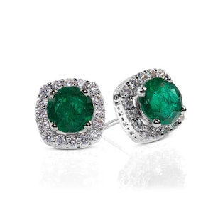 Pode incluir: Um par de brincos de prata com uma esmeralda verde e um halo de pequenas pedras brancas.