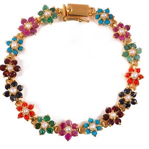 Può includere: Bracciale dorato con design floreale. Ogni fiore è composto da pietre preziose colorate, tra cui rosso, verde, blu e viola, che circondano una perla centrale. Il bracciale ha una chiusura sicura.