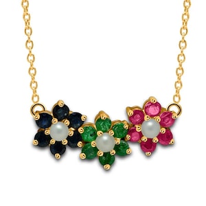 May include: A gold necklace featuring three flower pendants. Each flower is composed of colorful gemstones: blue sapphires, green emeralds, and red rubies, with a pearl center. The necklace has a delicate chain.