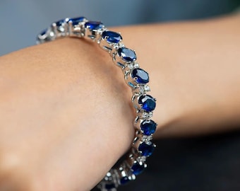 May include: A silver bracelet with a row of oval-shaped blue gemstones and smaller clear gemstones.