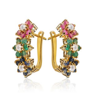 Op de afbeelding: Gouden creolen met een bloemmotief met roze, groene, blauwe en witte edelstenen.