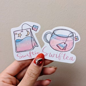 May include: Two stickers featuring Swifttea designs. One shows a tea bag with a moon and star, the other a teacup with a tea bag. Both have pink and blue gradients and the word "Swifttea" in a cursive font.