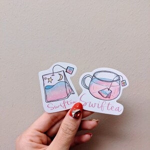 May include: Two stickers with a tea theme. One sticker shows a tea bag with a moon and stars, the other shows a teacup with a tea bag inside. Both stickers have the word "Swifttea" written on them.