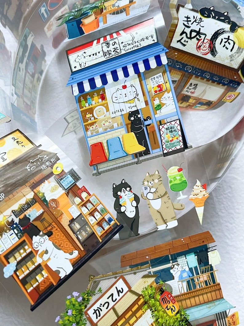 May include: A collection of colorful cat-themed stickers featuring Japanese-style shops and cafes. The stickers include illustrations of cats, food, and Japanese text. The stickers are in various shapes and sizes.