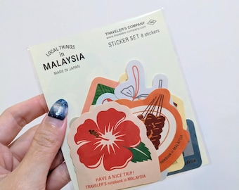 May include: A pack of eight stickers with Malaysian designs. The stickers depict a red hibiscus flower, food illustrations, and text that reads "Local Things in Malaysia" and "Have a Nice Trip!" The set is from Traveler's Company.