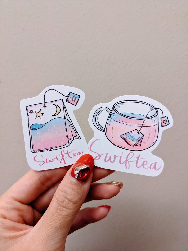 May include: Two stickers featuring Swifttea designs. One shows a tea bag with a moon and stars, the other a teacup with a tea bag inside. Both have a pink, blue, and purple gradient and the word "Swifttea" in pink script.