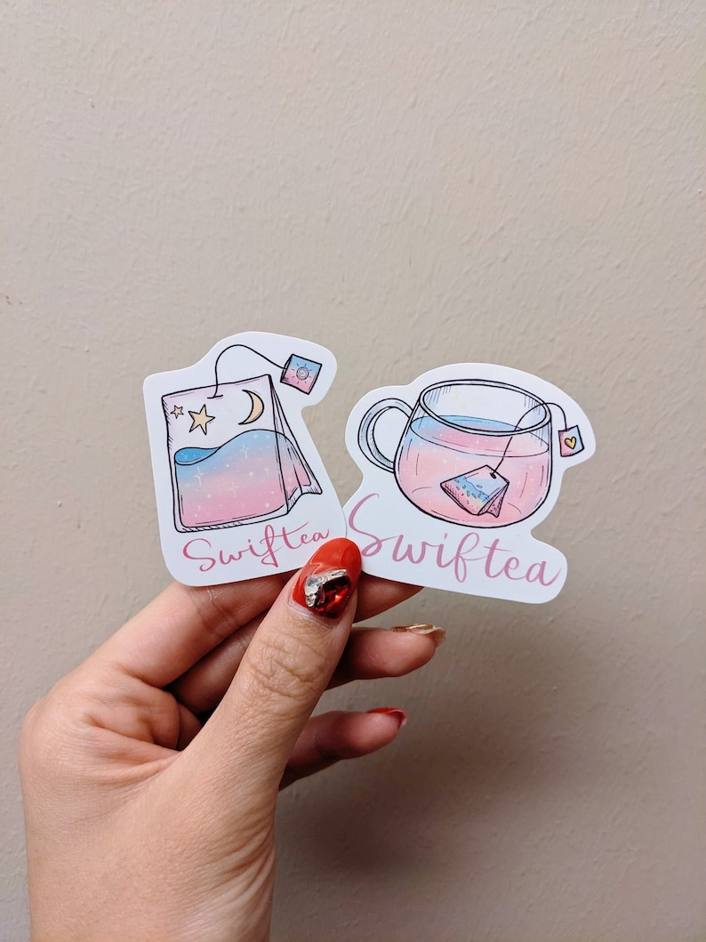 May include: Two stickers featuring Swifttea designs. One shows a tea bag with a moon and star, the other a teacup with a tea bag. Both have pink and blue gradients and the word "Swifttea" in a cursive font.