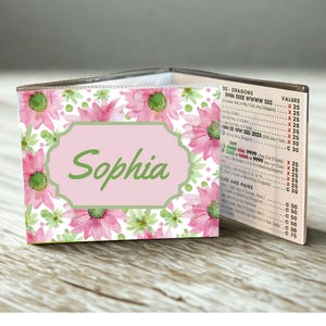 May include: A Mah Jongg card holder featuring a watercolor floral pattern of pink and green flowers on a white background. A central light pink label with a green border displays the name Sophia in green script. The side shows a printed score chart.