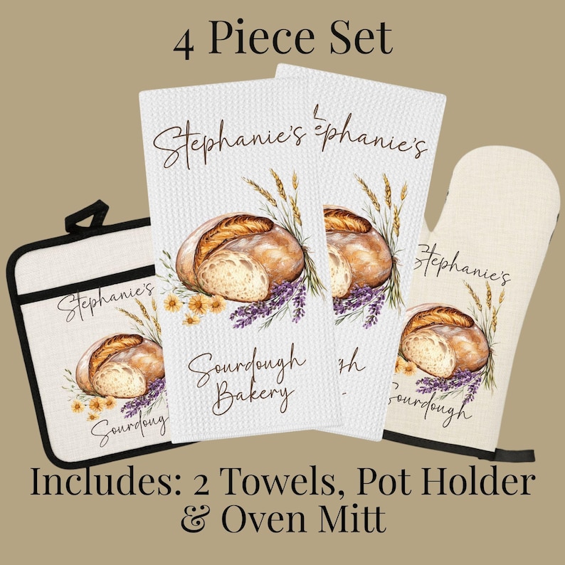 Op de afbeelding: Een 4-delige keukenset bestaande uit twee witte wafelstructuur theedoeken, een vierkante pannenlap en een ovenwant. Elk item is voorzien van een illustratie van zuurdesembrood, tarwearen en lavendel met de tekst Stephanie's Sourdough Bakery.