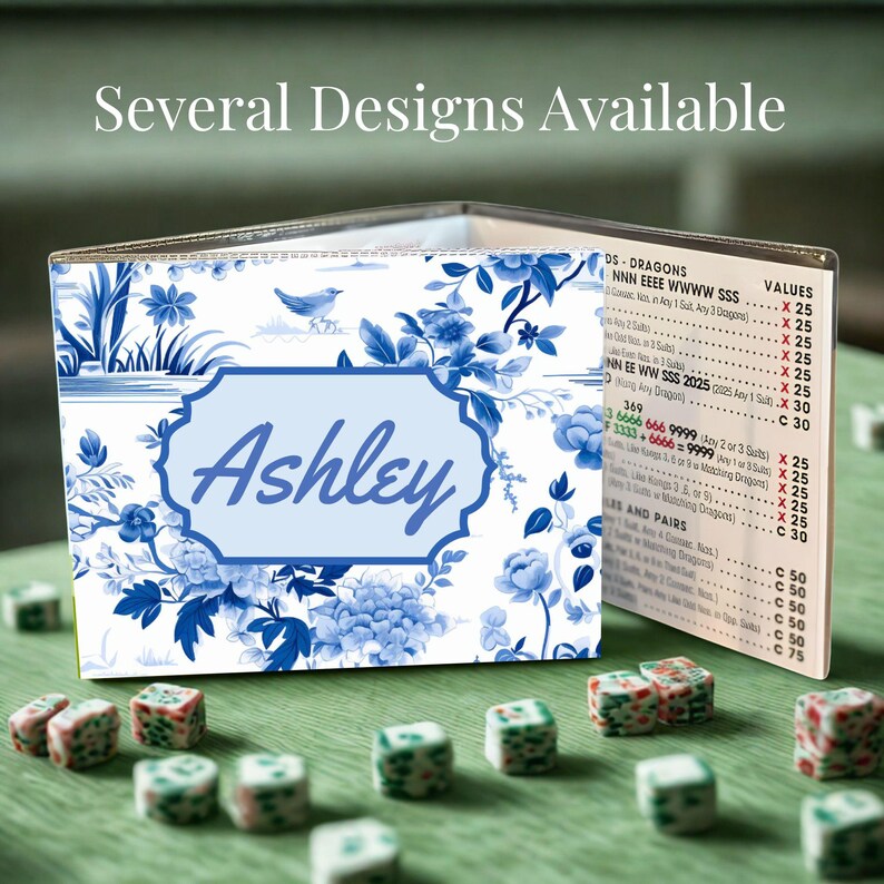 May include: A folding game score card featuring a blue and white floral pattern with a bird illustration and the name Ashley in a central light blue frame. The interior panel displays a printed list of game rules and point values for Mahjong.