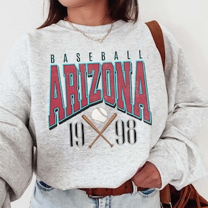 May include: Gray sweatshirt with a vintage-style graphic print that says "BASEBALL ARIZONA 1998" with a baseball and crossed bats.
