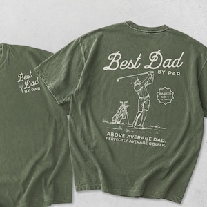 Puede incluir: Dos camisetas verde oliva. Una camiseta tiene impreso "Best Dad BY PAR" en la parte delantera. La otra camiseta tiene un gr&aacute;fico con tem&aacute;tica de golf en la parte posterior con el texto "Best Dad BY PAR", un golfista y las palabras "Above Average Dad. Perfectly Average Golfer."