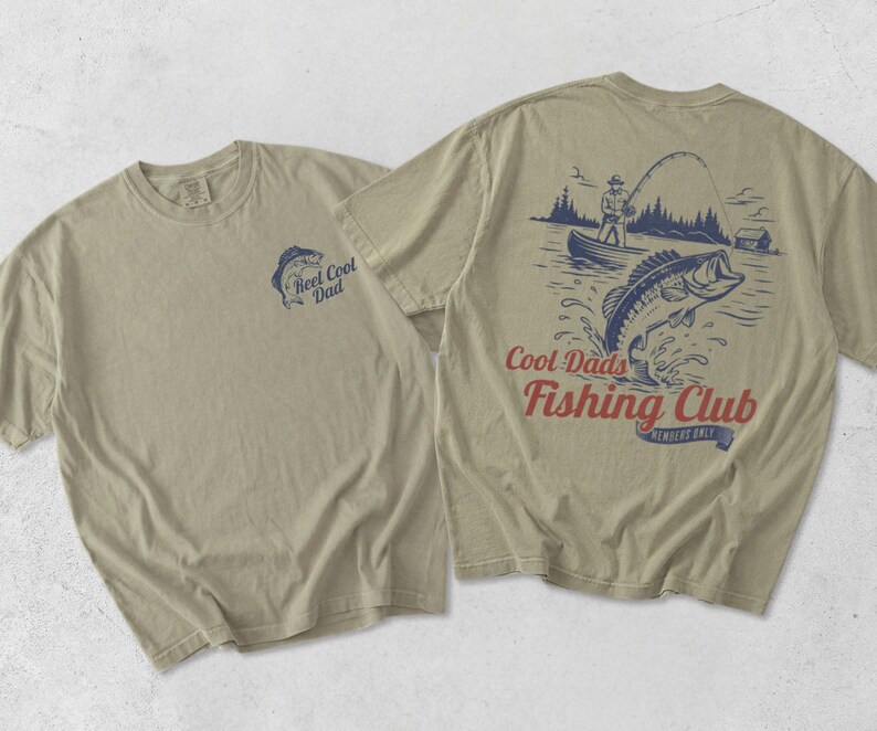 May include: Two beige t-shirts. One has a small blue graphic of a fish and the text "Reel Cool Dad." The other shirt has a larger graphic of a fisherman, a fish jumping out of the water, and the text "Cool Dads Fishing Club."