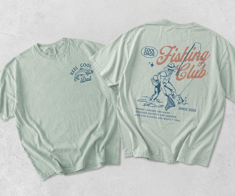 May include: Two light green t-shirts. One features a fish graphic and the text "REEL COOL Dad". The other displays a fisherman graphic and the words "COOL DADS Fishing Club SINCE 2026". The text "WHERE LEGENDS ARE MADE, WEATHER REPORTS ARE IGNORED, AND THE STORIES ARE MOSTLY TRUE" is also printed on the shirt.