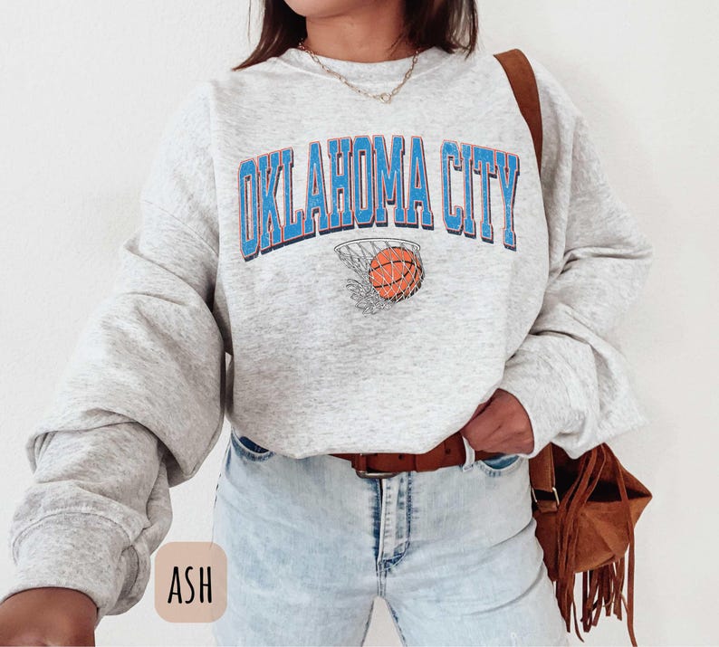 May include: Grey sweatshirt with the text "Oklahoma City" in blue and a basketball in a net. The sweatshirt has long sleeves and a crew neck.