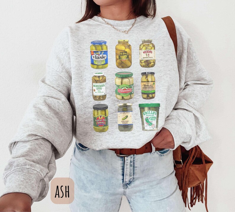 Op de afbeelding: Lichtgrijze sweatshirt met een afbeelding van verschillende augurkenpotten. De potten hebben verschillende vormen en maten, met labels zoals Vlasic en Claussen. De sweatshirt heeft lange mouwen en een ronde hals.