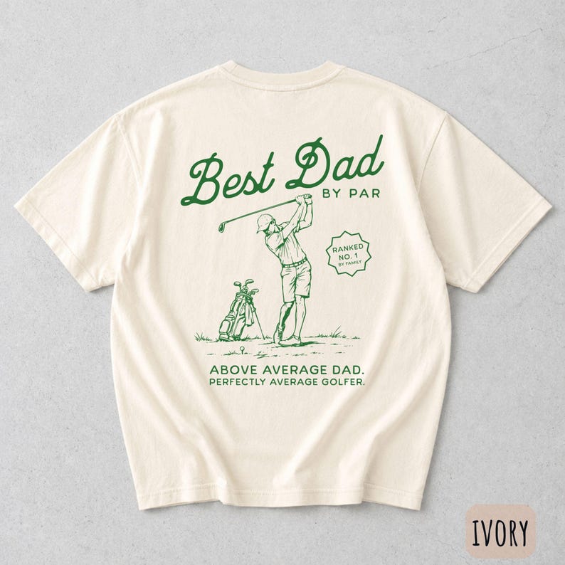 Puede incluir: Camiseta de color marfil con un gr&aacute;fico verde de un golfista y el texto "Best Dad by Par". El dise&ntilde;o incluye "Above Average Dad. Perfectly Average Golfer." Tambi&eacute;n hay una bolsa de golf.