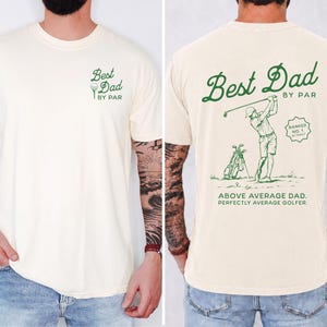 Puede incluir: Camiseta color crema con el texto "Best Dad by Par" y un gr&aacute;fico de pelota de golf en la parte delantera. La parte trasera presenta una ilustraci&oacute;n con tem&aacute;tica de golf y el texto "Best Dad by Par".