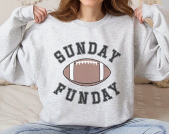 Puede incluir: Sudadera gris con un gráfico en blanco y negro de un balón de fútbol y el texto "SUNDAY FUNDAY".