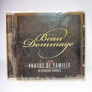 May include: A CD case with a black leather-like background and gold lettering. The title is "Beau Dommage" and the album is "Photos de Famille" with the text "16 chansons choisies".