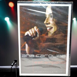 May include: A DVD case featuring a woman singing into a microphone. The case is red and white with the text "Ana Carolina Estampado" and "Um instante que não para".