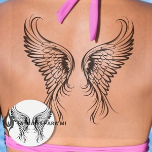 Könnte beinhalten: Schwarzes temporäres Tattoo von Engelsflügeln auf dem Rücken einer Person. Die Flügel sind detailliert und haben ein gefiedertes Design.