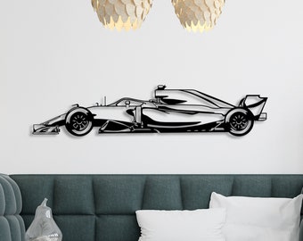 May include: A black and white silhouette of a race car mounted on a white wall above a teal sofa. The car is facing the left side of the image.